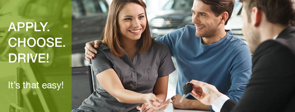 A young couple is handed keys to their new car from a dealership employee. The text on the image reads "Apply. Choose. Drive! It's that easy!"