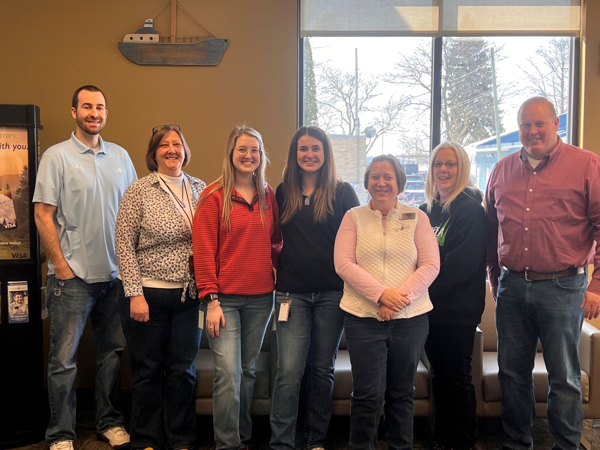 a group of seven Forest Area Federal Credit Union standing in a row and smiling. 