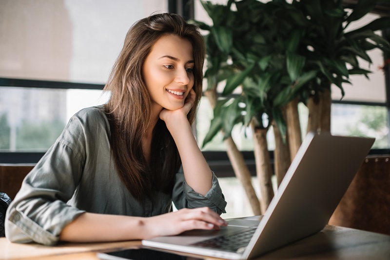 a young women sits are her computer to log into her Forest Area Federal Credit Union online banking.